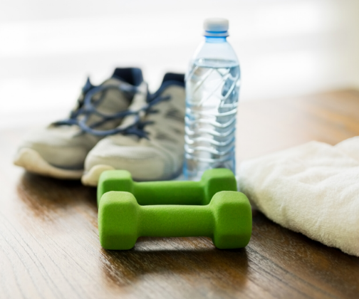 Trainers, water bottle, exercise weights and towel on floor.