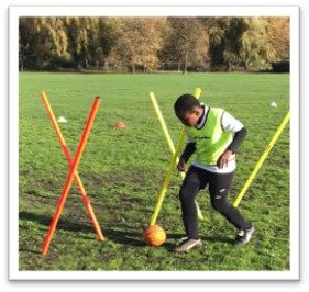 Boy dribbling ball through posts