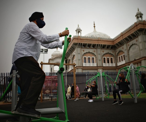 Man using a step machine at an outdoor gym.