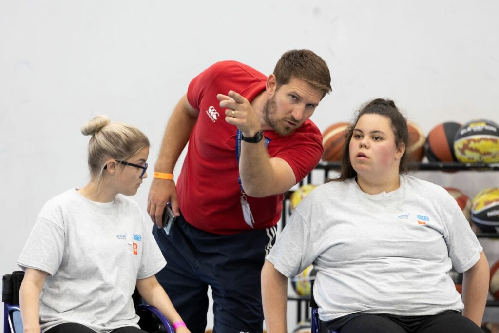 coach speaking to two girls in wheelchairs