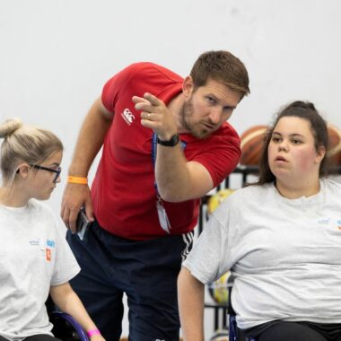 two girls in wheelchairs speaking with coach