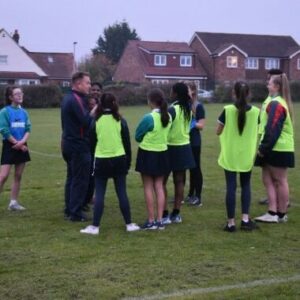 group of girls on sports field with coach