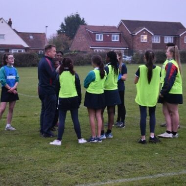 group of girls on sports field with coach