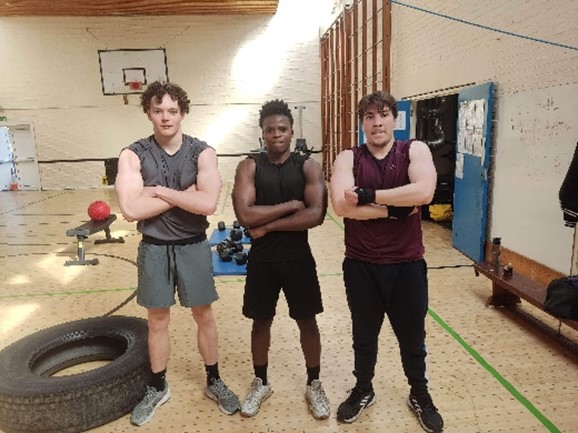 three young men standing in a boxing gym