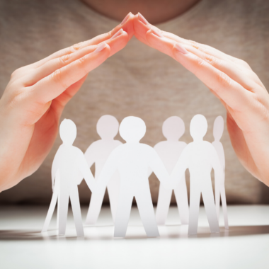 hands cupped above a chain of silhouetted people cut out of paper