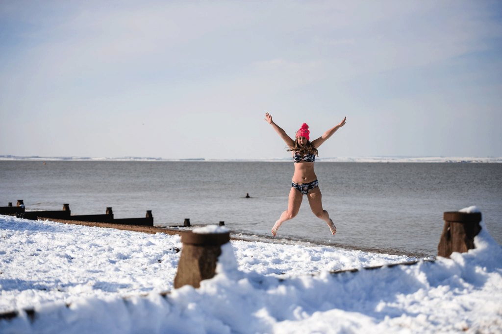 women in bikini jumping in the snow on the beach