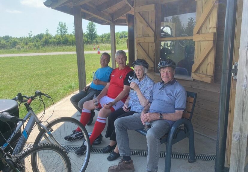 Four people with cycling helmets sat down smiling to camera