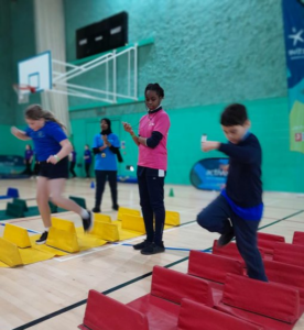 boy running over hurdles with young girl watching