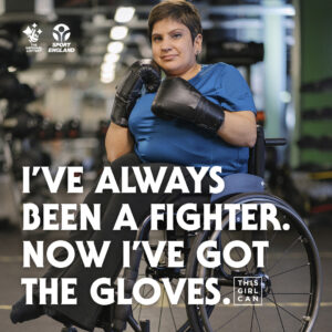 woman sat in a wheelchair in a gym with boxing gloves