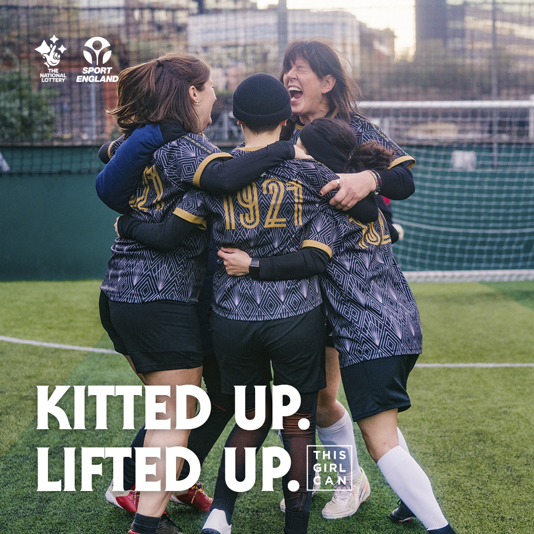 Group of women on football pitch hugging and smiling