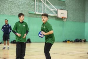 two young people in sports hall playing dodgeball