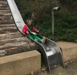 Elderly man sliding down a slide