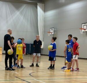 young people playing basketball in a sportshall