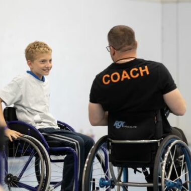 Basketball coach in a wheelchair speaking to young person in wheelchair