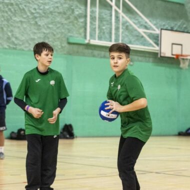 two young people in sports hall playing dodgeball