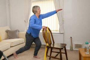 lady holding onto chair stretching her arm out in the air