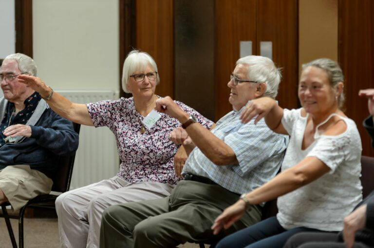 older people seated and moving their arms