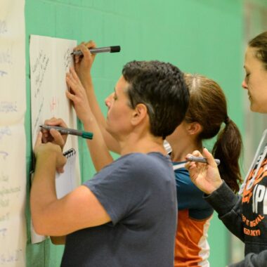 people in a sports hall writing down notes