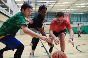three men in sports hall playing basketball
