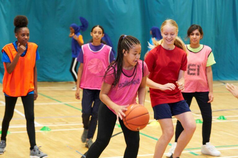 group of girls playing basketball in a sports hall