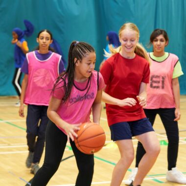 group of girls playing basketball in a sports hall