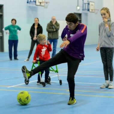 boy kicking football in sports hall