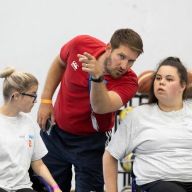 coach speaking to two girls in wheelchairs