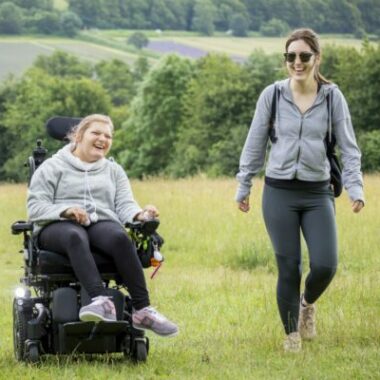 two people walking alongside a person using a mobility scooter