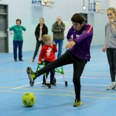 boy kicking football in sports hall