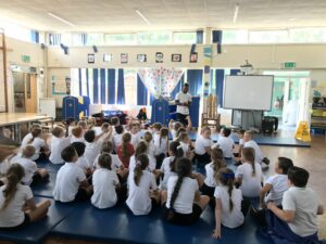 children sitting on gym mats listening to Courtney Tullochs story