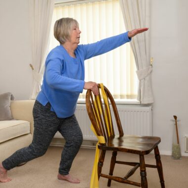 lady holding onto chair stretching her arm out in the air