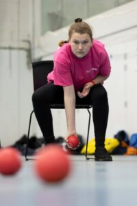 Young person sat on chair playing boccia