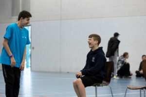 Young person laughing with a young leader whilst playing boccia