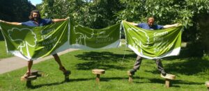 two park rangers holding up Green Flag Award banners