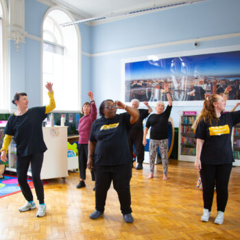 Group of people in a library taking part in a dance session