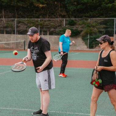 man bouncing ball on a tennis racket on an outside court