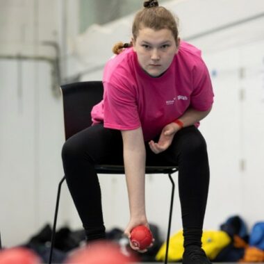 Young person sat on chair playing boccia