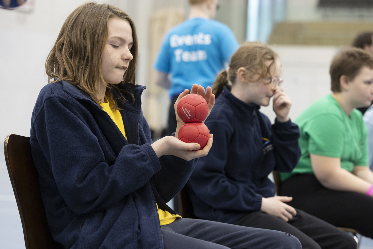 Young person holding two boccia balls
