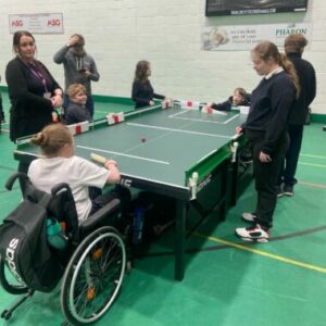 Group of young people playing table cricket in a sports hall
