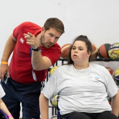 coach speaking to two girls in wheelchairs