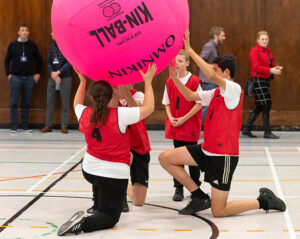 Group of young people playing Kin ball in sports hall