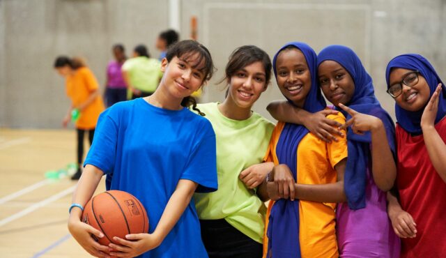 group of girls standing in a sports hall smiling
