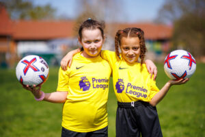 two young girls holding footballs