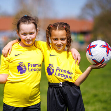 two young girls holding footballs
