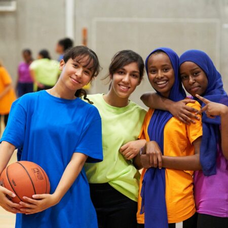 group of girls standing in a sports hall smiling