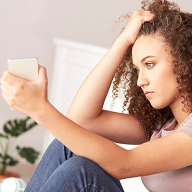 Young person sat with phone in their hand