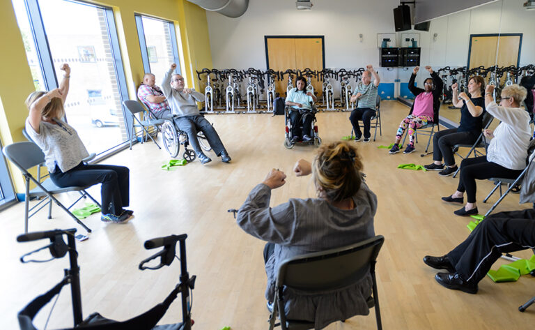 gruop of people doing seated exercise in a community hall