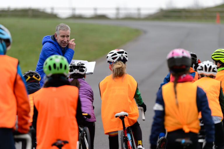 Coach speaking to a group of children on bikes