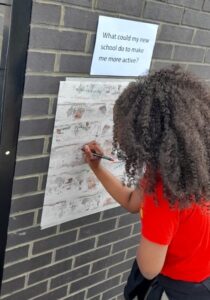 Young person writing on a 'graffiti wall' poster