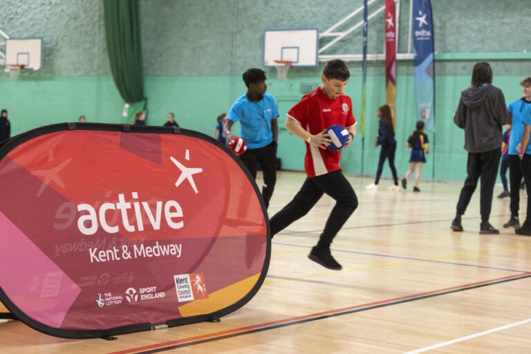 young person running with a ball in a sports hall